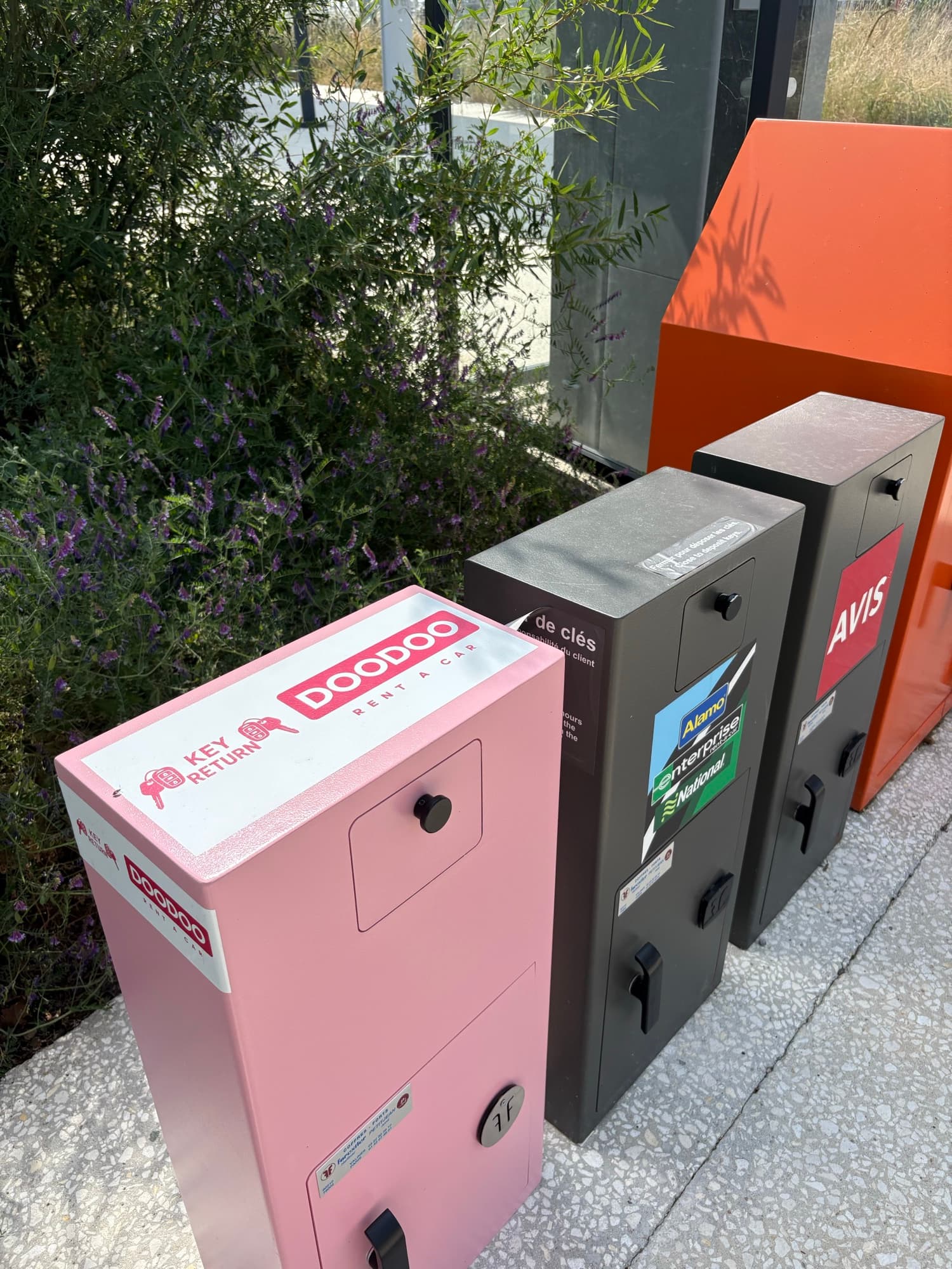DOODOO key-return box standing next to Avis, Enterprise, Alamo and National at a French airport