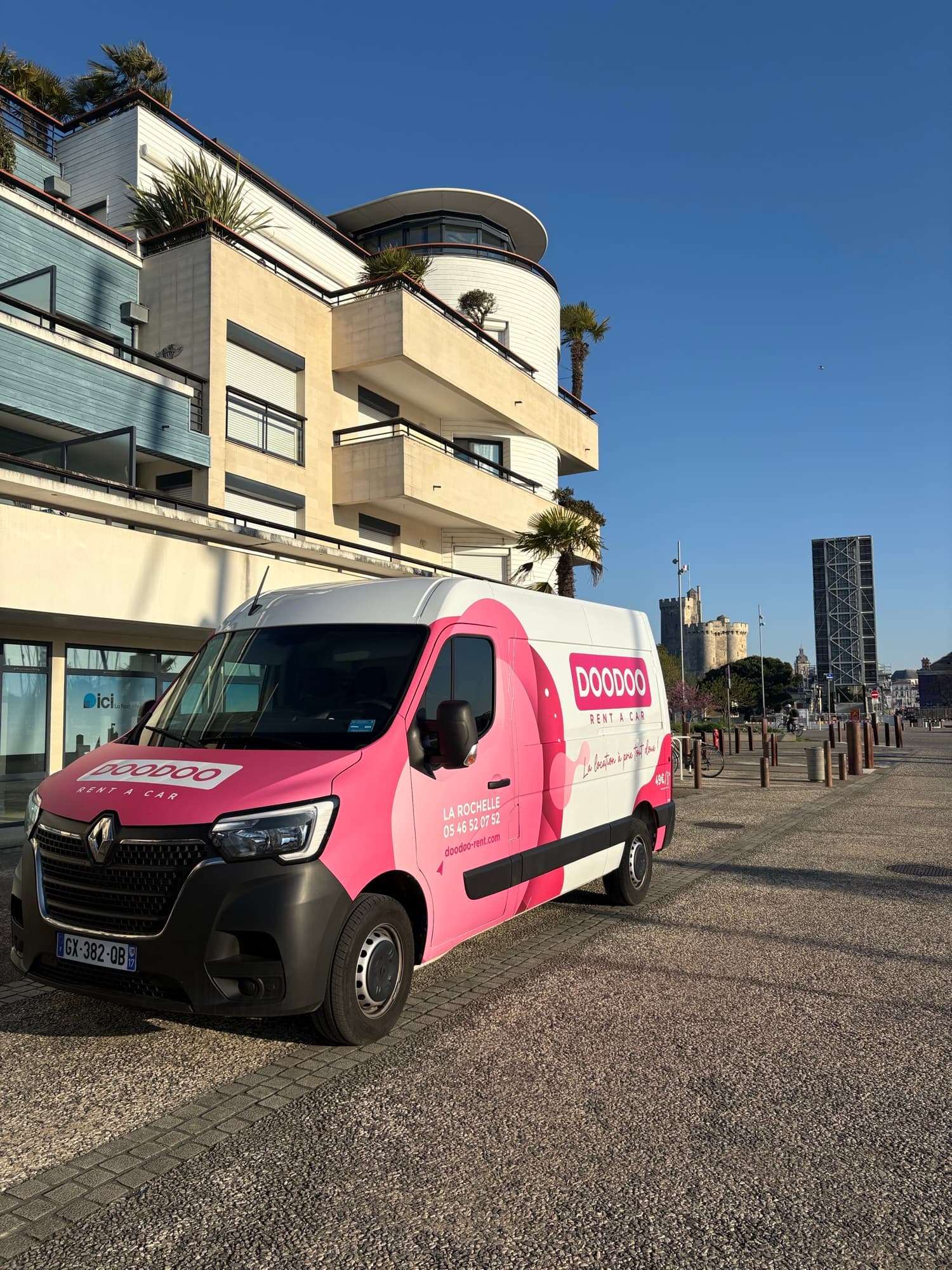 DOODOO branded van parked on the La Rochelle waterfront, historic towers in the background